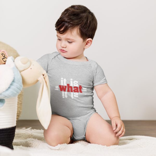 A baby wearing a gray onesie playing with a stuffed animal.