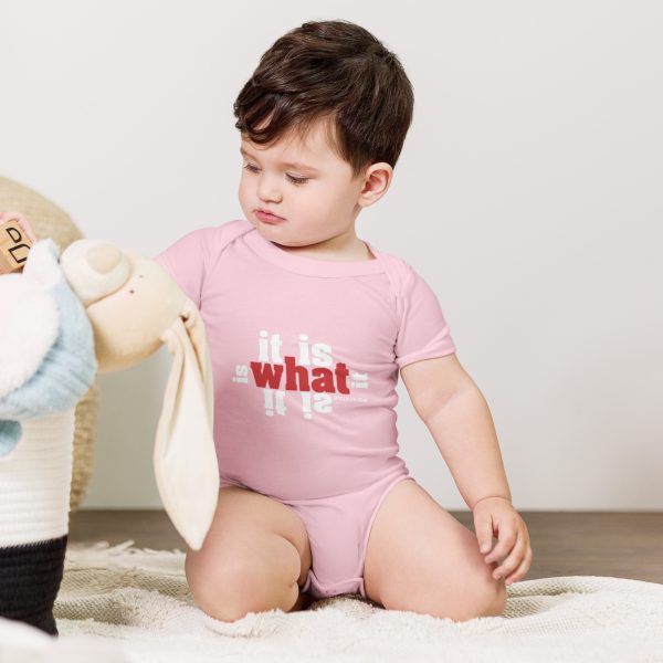 A baby in pink shirt playing with stuffed animal.