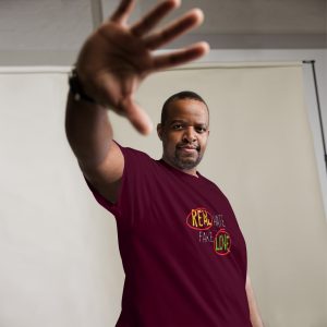 A man in maroon shirt raising his hand.